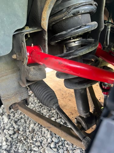 Customer's bright red tubular upper control arm installed on the front suspension of a truck.