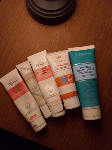 Reviewer's Eco Pigmentation Bundle products, including creams, sunblock, and face wash tubes on a wooden surface.