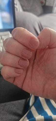 Reviewer's hand showing natural nails with simple, smooth, dusty-rose First Kiss gel polish applied.