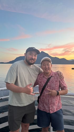 Customer's Big Relaxed Cap worn by a man posing outdoors near water at sunset.