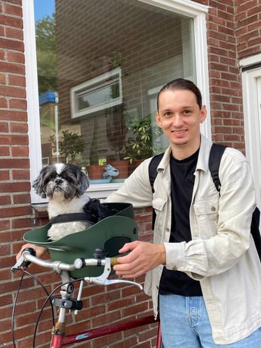 Reviewer's green Kvisp Dog Bike Carrier mounted on a bicycle with a small dog sitting comfortably inside.