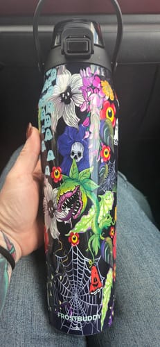 Reviewer's hand holding the floral and skull patterned Toxic Bloom Bottle Buddy with a black carry handle.