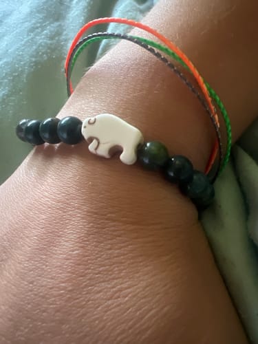 Customer's Mystery Bracelet with dark beads and a white bison charm worn on their wrist.
