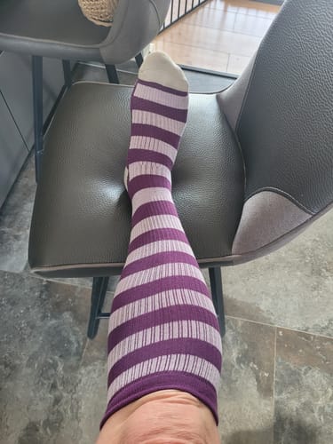 Customer's lilla og hvide stribede Diasocks støttestrømpe på en stol, der yder komfort.