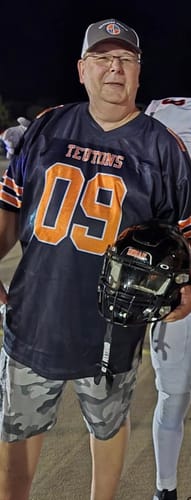 Customer's navy and orange football jersey with the number 09, worn while holding a black football helmet.
