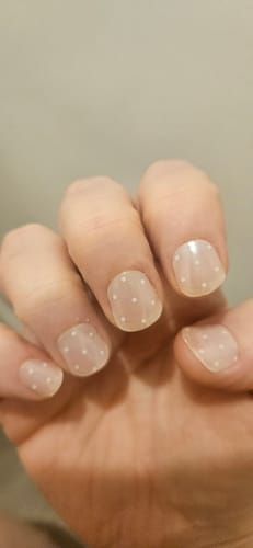 Customer's hand showcasing the Pearl Polka gel nail stickers with small white dots on a sheer base.