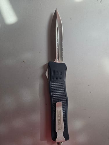 Customer's Blue Phantom D/A OTF knife in black, showing the deployed, partially serrated blade and pocket clip.
