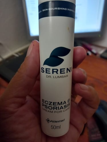 Customer's hand holding a white 50ml bottle of Sereni Eczema & Psoriasis Cream for Care.