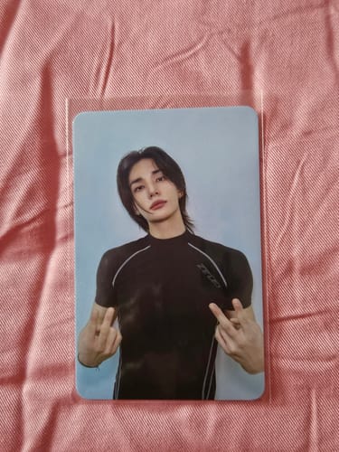 Customer's Stray Kids photocard in a clear sleeve, showing a person posing with a peace sign on a light background.