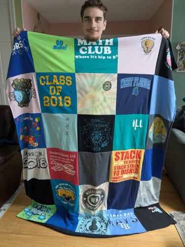 Customer's Project Repat T-Shirt Quilt held by a person, featuring colorful panels of various shirts.
