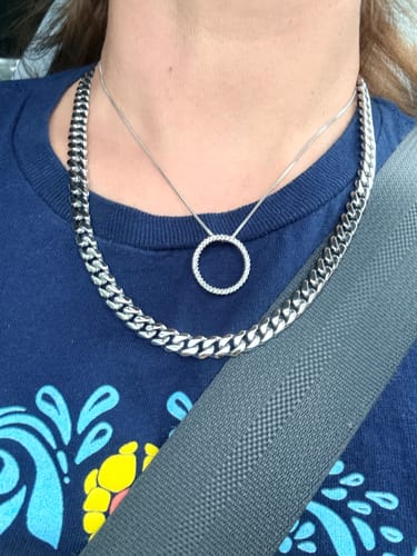 Customer's Cuban Chain worn around the neck, styled with a thin pendant necklace over a blue t-shirt.