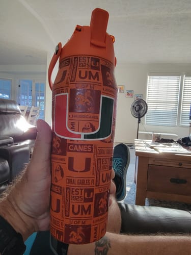 Customer's orange Miami Hurricanes Bottle Buddy held in hand in a living room.