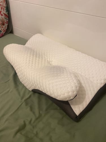 Reviewer's white ergonomic Pillowen visco yastık placed on a green bed sheet.