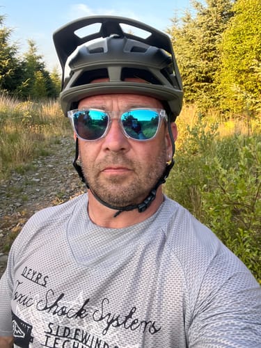 Customer's Alchemist Short Sleeve Flowteq Jersey in grey, worn by reviewer with helmet and glasses on a trail.