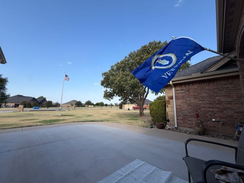 Customer's view from a patio showing the 20 ft. Commercial Flagpole in the distance, alongside a blue garden flag.