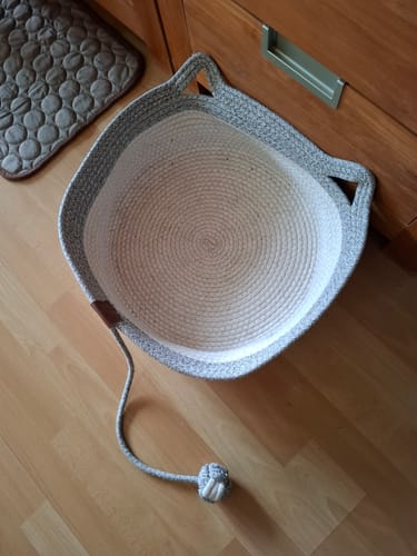 Kunden Fellnest Katzenkorb aus grau-weißem Tau mit Spielzeug, platziert auf dem Boden.