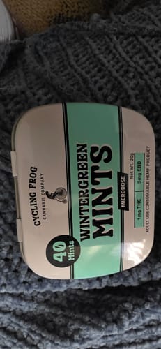 Customer's Wintergreen Mints tin sitting on a textured grey fabric surface.