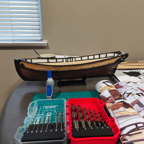 Customer's Polaris Starter Pack model ship under construction on a desk with tools, glue, and instruction papers.