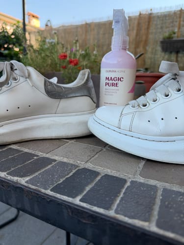 Customer's Magic Pure spray bottle next to a pair of white sneakers on an outdoor table.