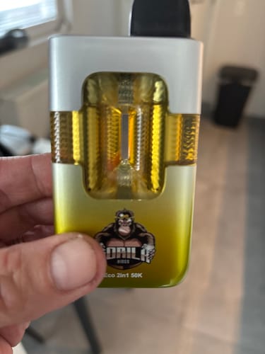 Customer's hand holding the yellow Fumot Eco 2 in 1 50000 Puffs Disposable Vape, showing the transparent liquid tanks.