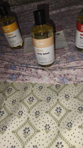 Customer's three Yummy Body Splash oil bottles on a floral patterned bed sheet.