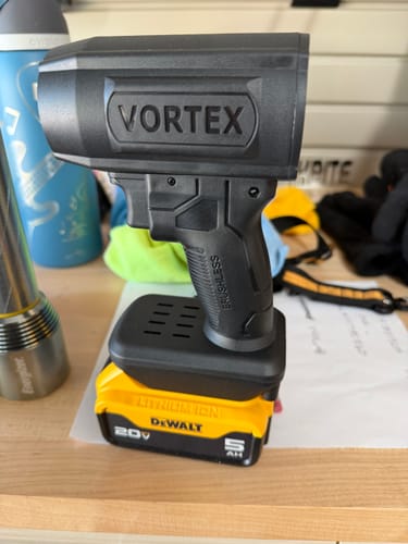 Customer's black Vortex blower attached to a yellow DeWalt battery, sitting upright on a table.