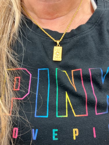 Customer's gold-toned The Sun Tarot Pendant Necklace worn on a chain against a person's chest.