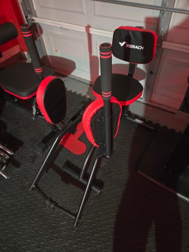 Reviewer's Seated Hip Abductor Machine for Home in a garage setting, showing its black and red design.