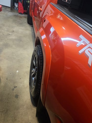 Customer's orange truck with installed wheel spacers, showing the tire extending past the fender for an aggressive stance.