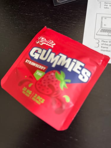 Customer's red ROLLZ THC Gummies strawberry packaging, close-up view.