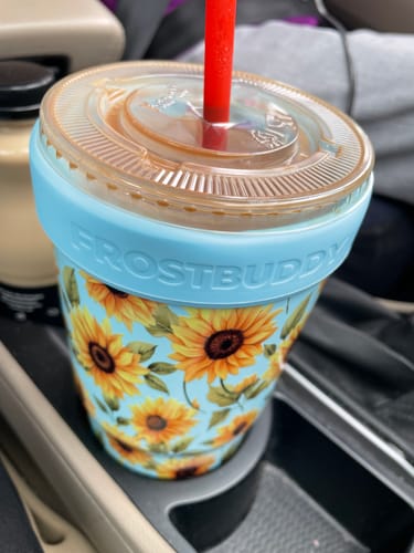 Customer's To-Go Buddy cup with sunflower pattern in a car cup holder, holding an iced coffee with a red straw.