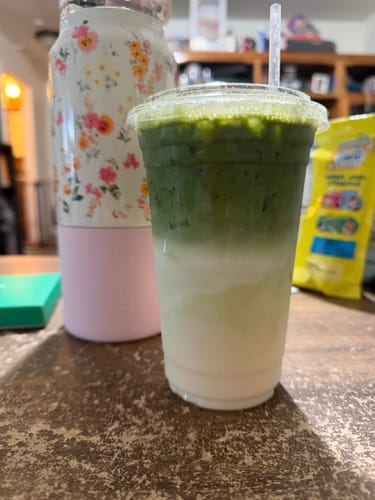 Customer's FLUR x Nami Matcha Set glass filled with a layered matcha latte on a wooden table.