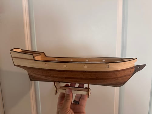 Reviewer's hand holding the wooden hull of the Maqueta Barco Albatros model ship in progress.