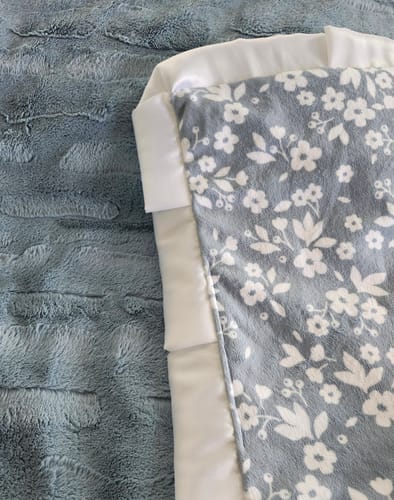 Customer's Dainty Floral Blue Blanket, showing a floral fabric side with white ruffle trim next to blue plush backing