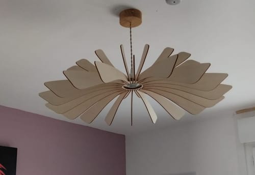 Customer's Aurora suspension light installed on a white ceiling with light wood, petal-shaped design elements.