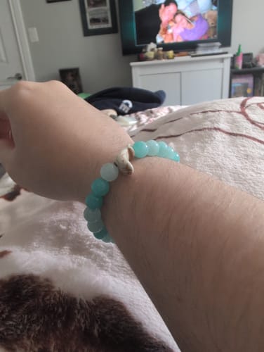 Customer's Odyssey Bracelet featuring round blue beads and a small charm on their wrist.