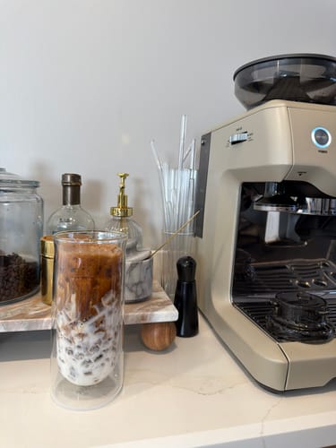 Customer's FLUR Family Set double-walled glass holding iced coffee on a home coffee station counter.
