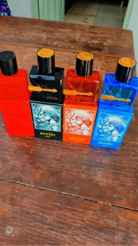 Customer's Kit Adonis e Attracione Men, featuring four colorful perfume bottles with bow and arrow designs on a table.