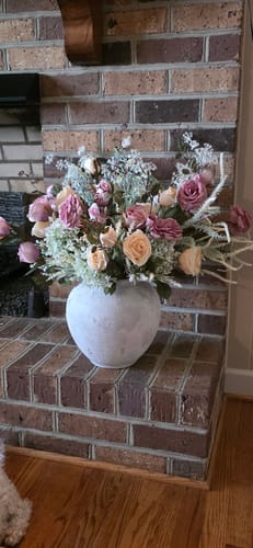 Customer's Layla Stone Vase filled with flowers sitting on a brick fireplace hearth.