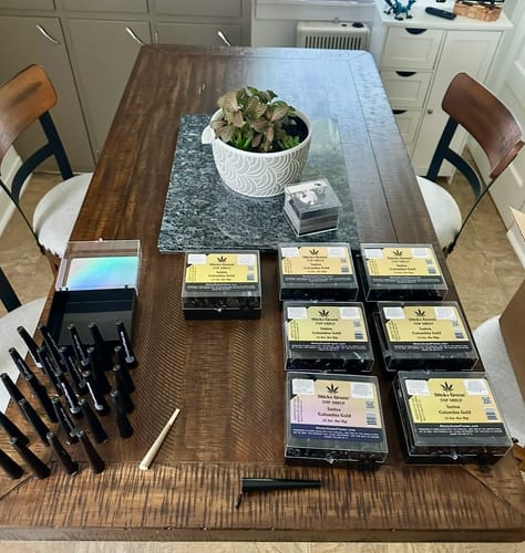 Customer's Pre Rolls 100ct displayed on a wooden table, including many individual pre-rolls and several labeled boxes.