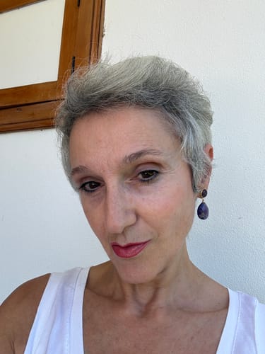 Customer's portrait wearing deep purple teardrop earrings resembling the Boucle d'oreille Labradorite Coquillage.