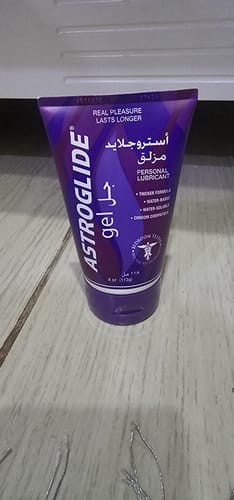 صورة من المراجع لعلبة مزلق أستروجلايد البنفسجية بتركيبة جل موضوعة على سطح خشبي.