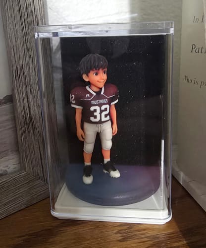 Customer's custom chibi-style football figurine inside a clear display case, wearing a dark maroon and white jersey.