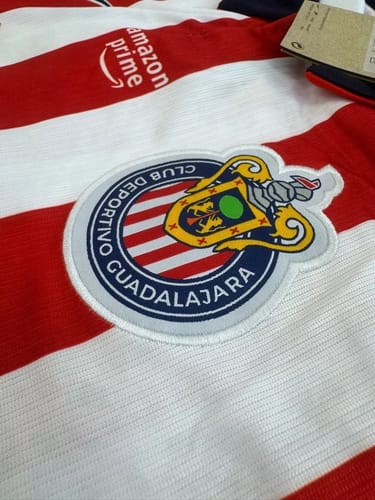 Reviewer's Chivas Guadalajara local jersey showing a detailed embroidered team emblem on red and white fabric.