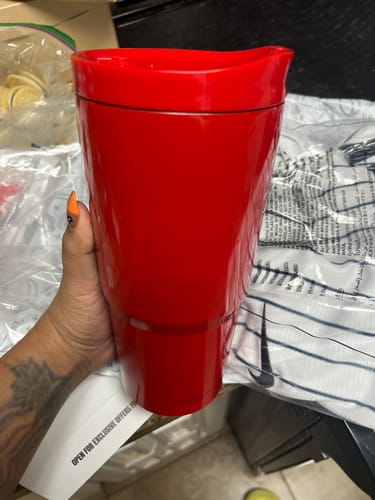 Reviewer's hand holding a vibrant red To-Go Buddy tumbler