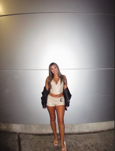 Reviewer wearing the sand Rebel Studded Faux Leather Set, featuring a halter corset top and studded micro shorts.